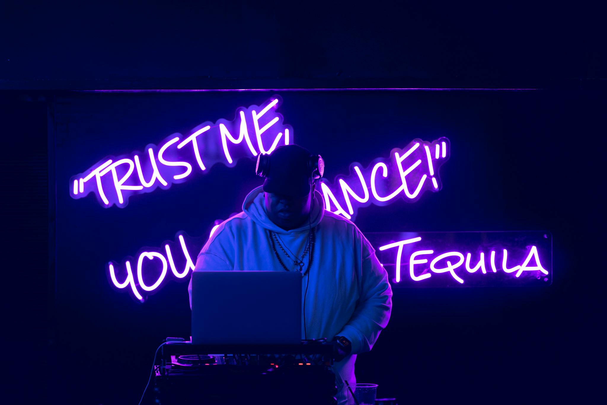 DJ playing music under neon lights with a laptop, enhancing the party vibe.